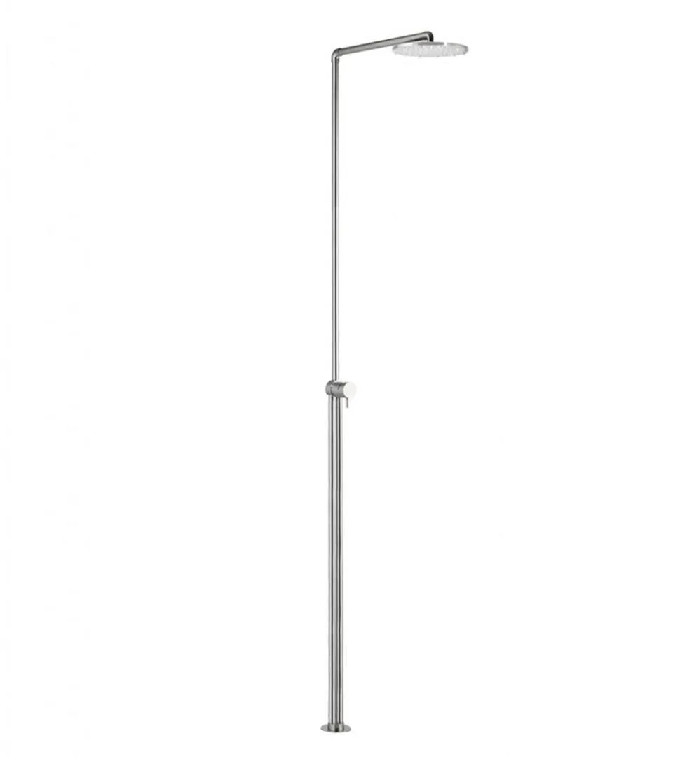 Freestanding brushed stainless steel shower column standing on a stone tray, with a slim vertical riser, a mixer at waist height and a round overhead head on a forward arm
